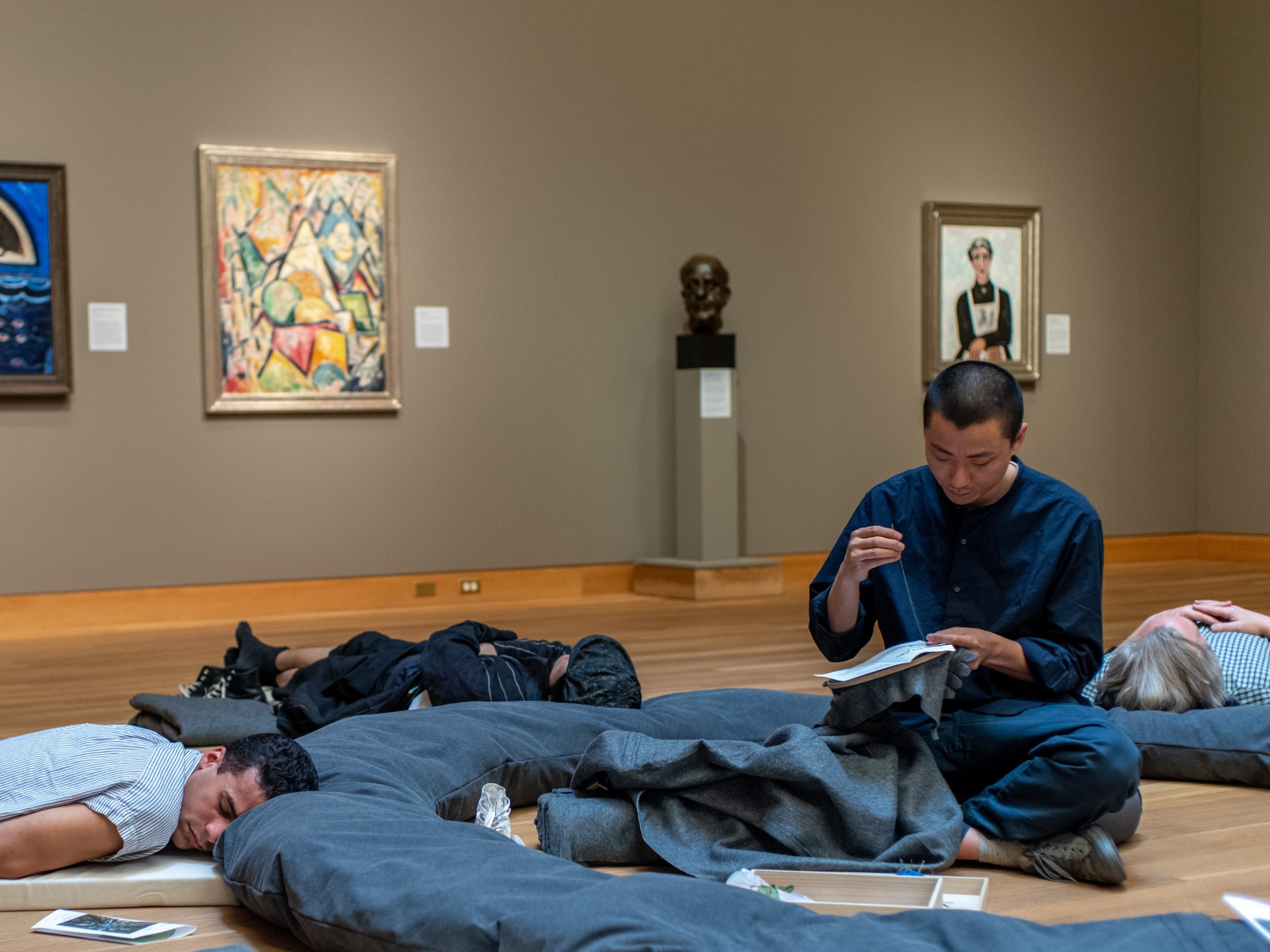 An image of people down on the ground 'napping' in an art gallery.