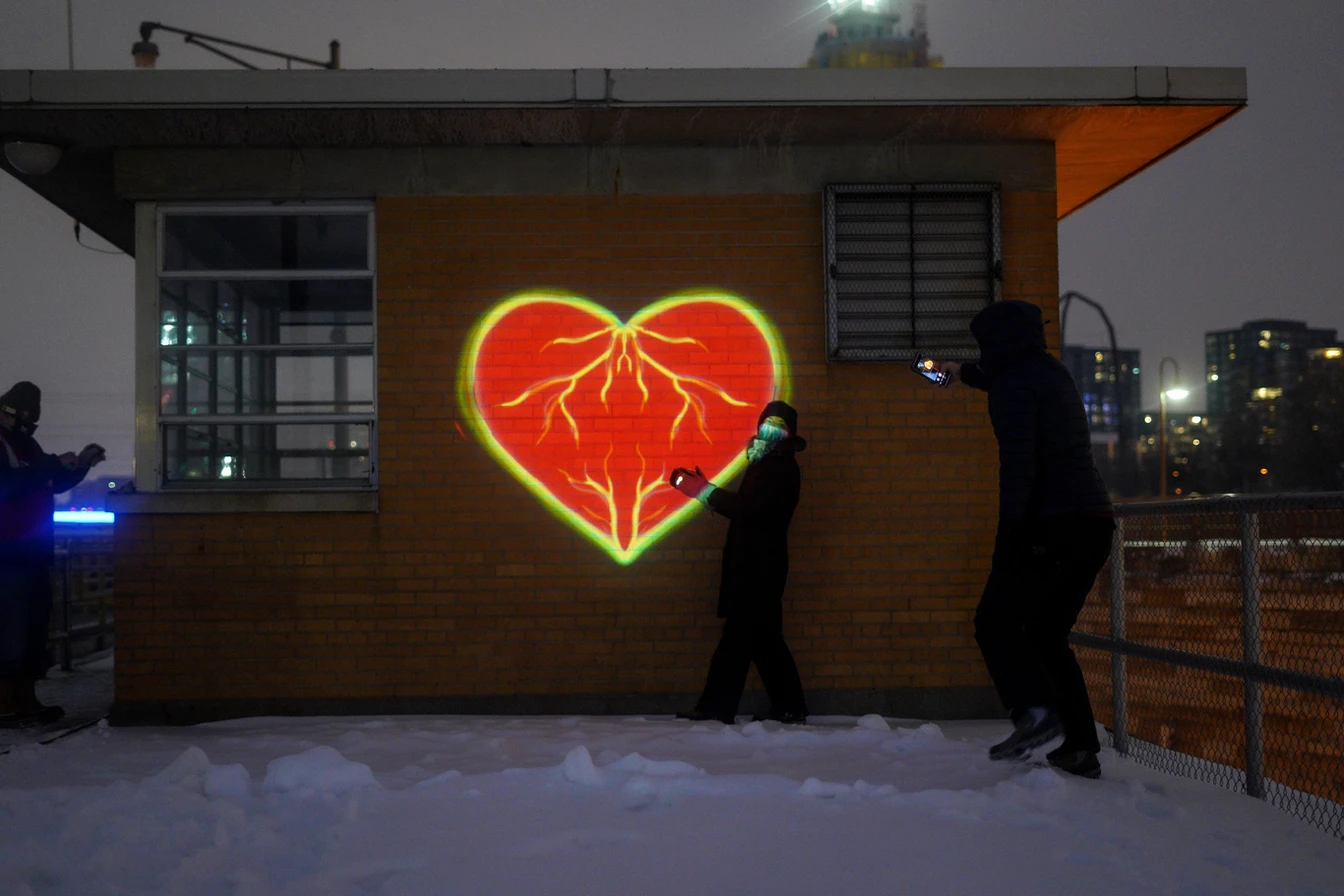 An image of a heart graphic projected onto a small building.