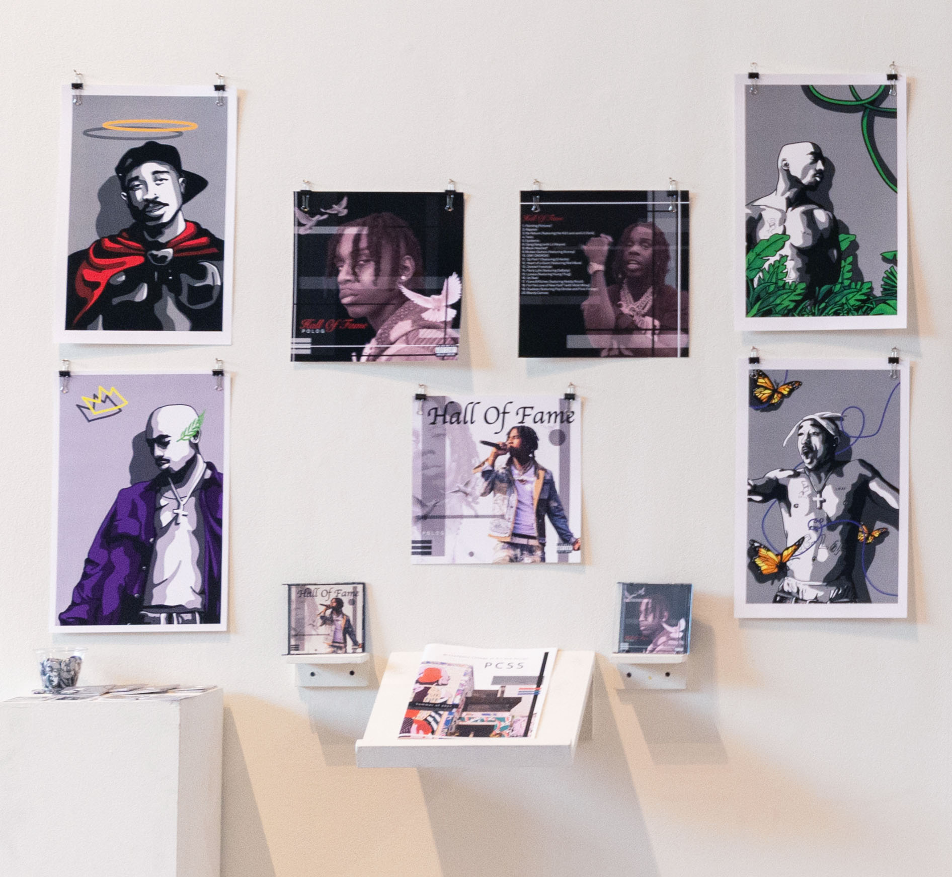 Graphic design student work featuring multiple images on a white wall. Rapper Tupac is featured in several images.