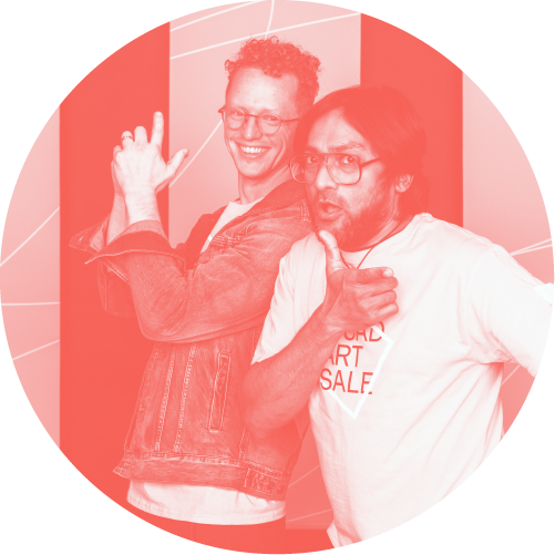Two people posing in front of a photo op wall