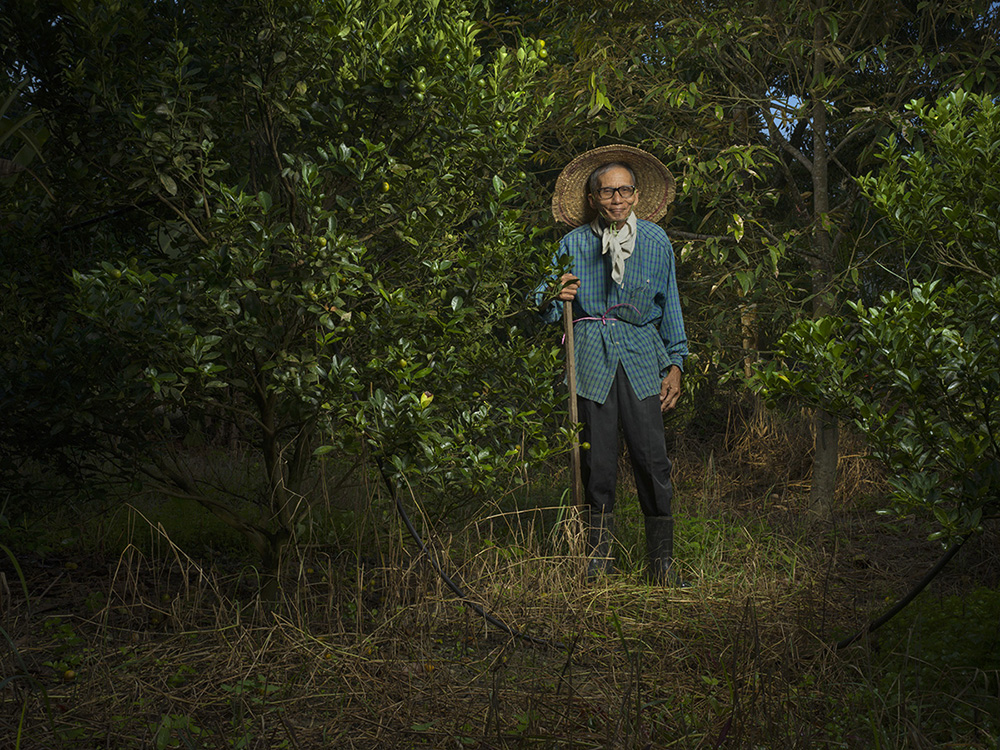 Photo of a man standing in a field with a gardening/farming tool