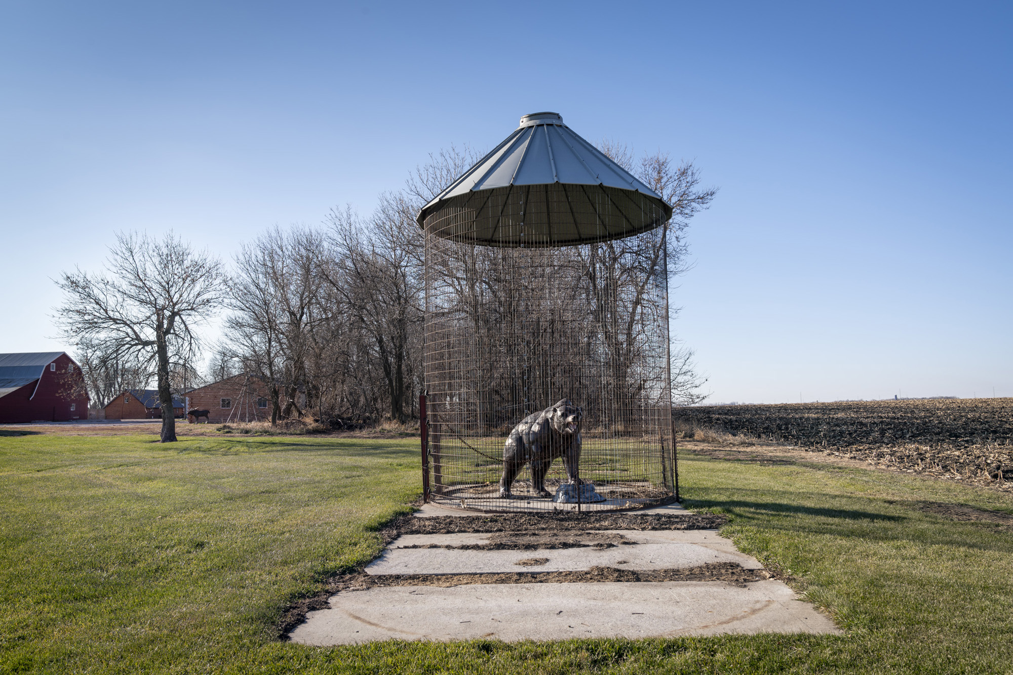 Photograph of a bear sculpture inside a silo shaped cage