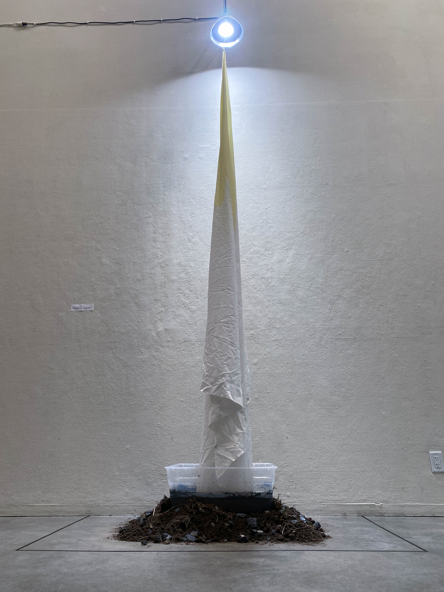 Installation with hanging fabric and a pile of dirt underneath