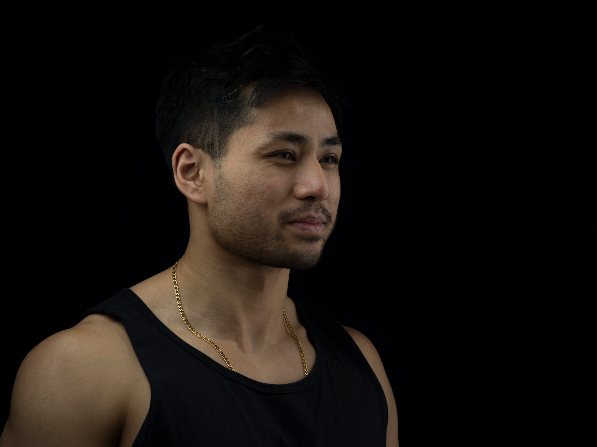 Photograph of a person wearing a black tank top on a black background