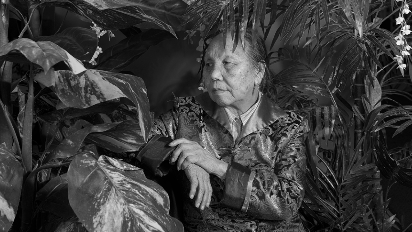 Black and white portrait of a woman surrounded by plants