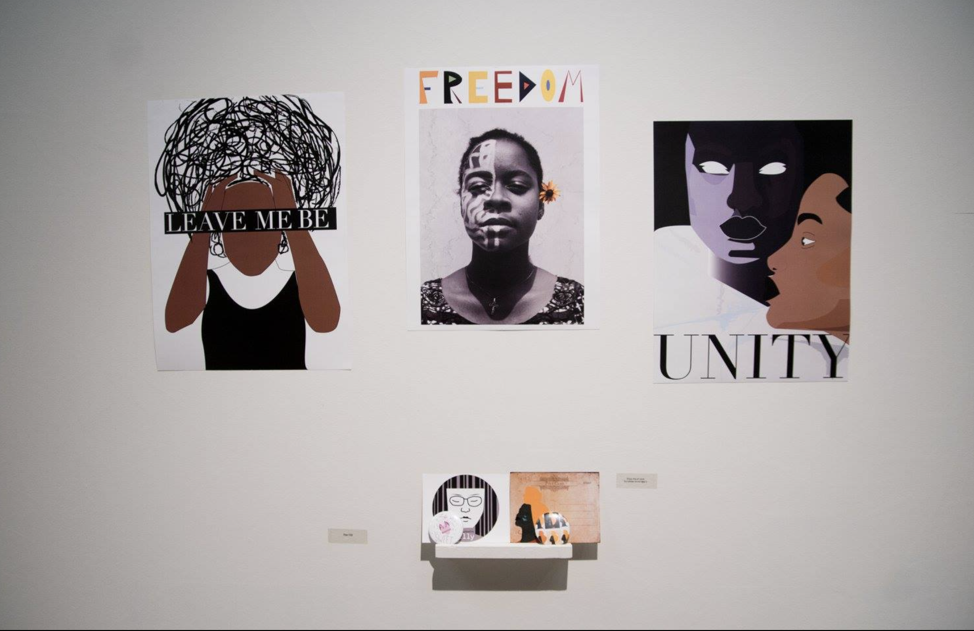Graphic design student work featuring three wall pieces with figures and text reads "leave me be," "freedom," and "unity"