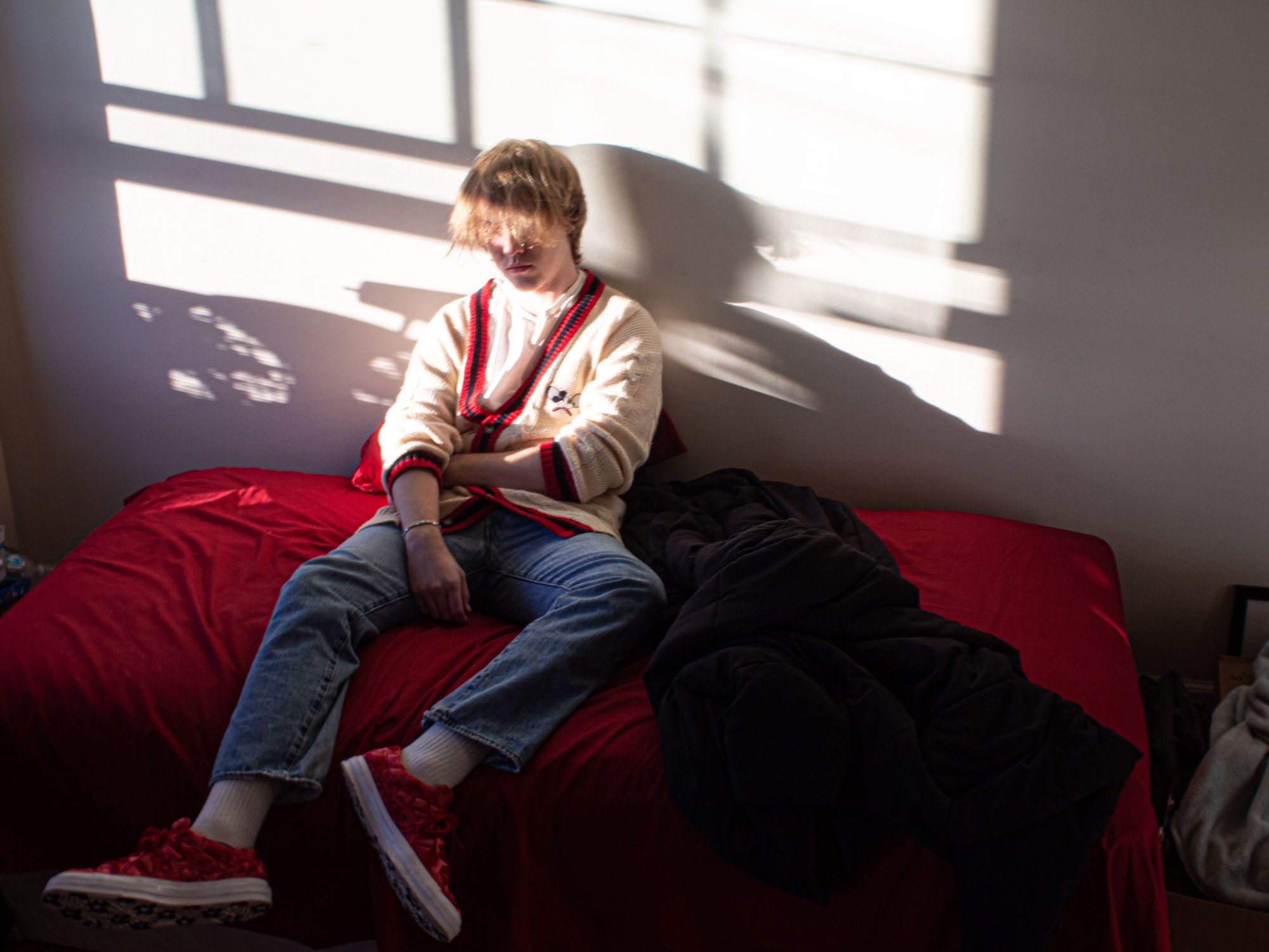 A photograph of a person sitting on a bed