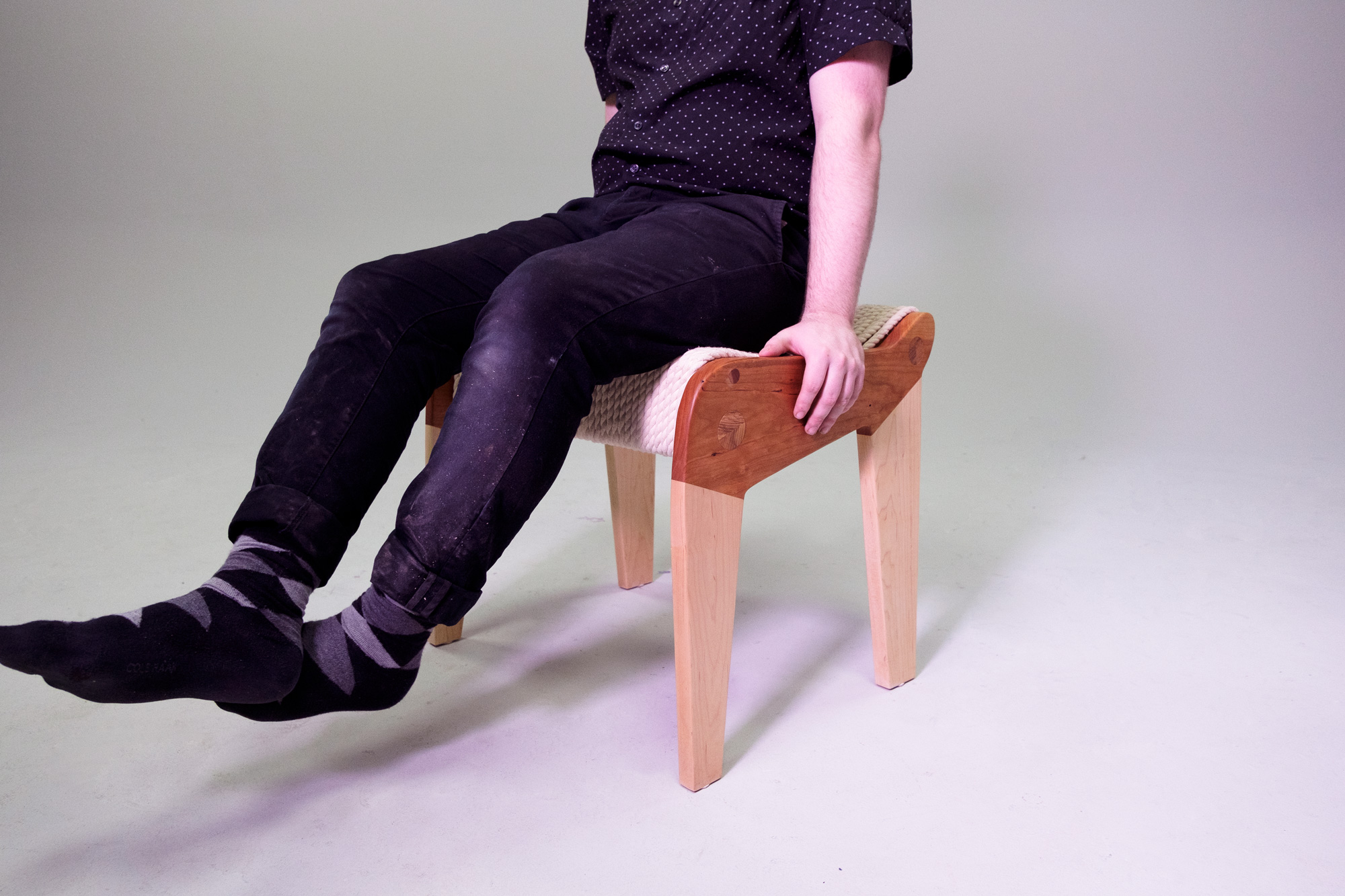 Person sitting on stool made with wood and rope