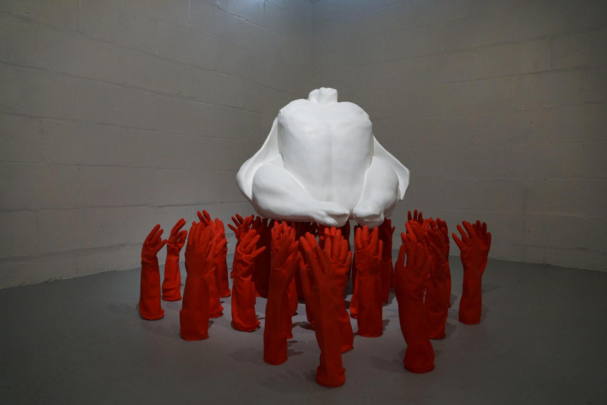 A sculpture installation of red latex gloves and a cast chicken