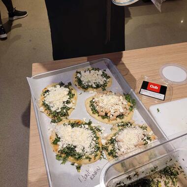 Five pita breads with greens, beans and cheese lay on a tray