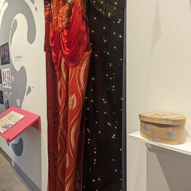 Entrance to black box theater, covered by bright red embellished curtain and string lights