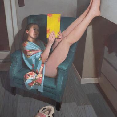 Person in robe reclines in chair reading a yellow book, smiling, with plush cow slippers in the foreground