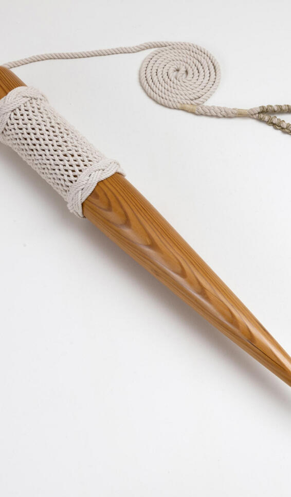 Hand carved wooden tool that has been polished and the top half wrapped in knitted string ; Brad Jirka