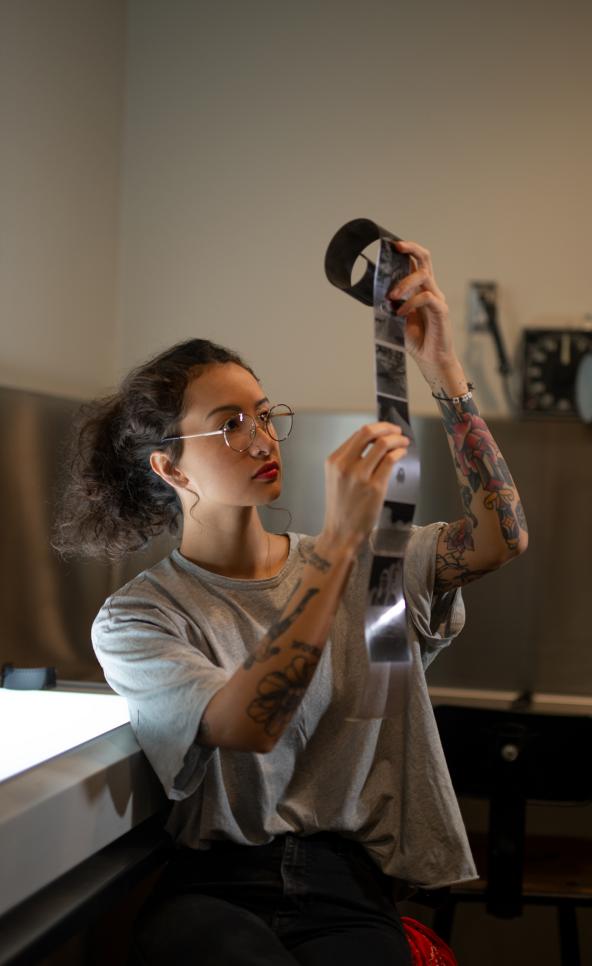 Person looking at film negatives in the dark room