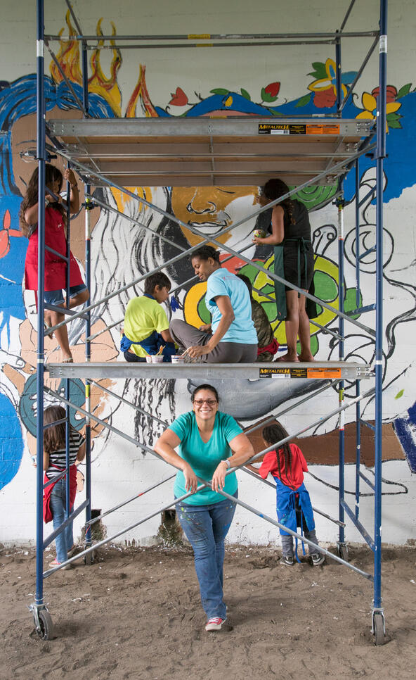 A group of people in front of an in-progress mural