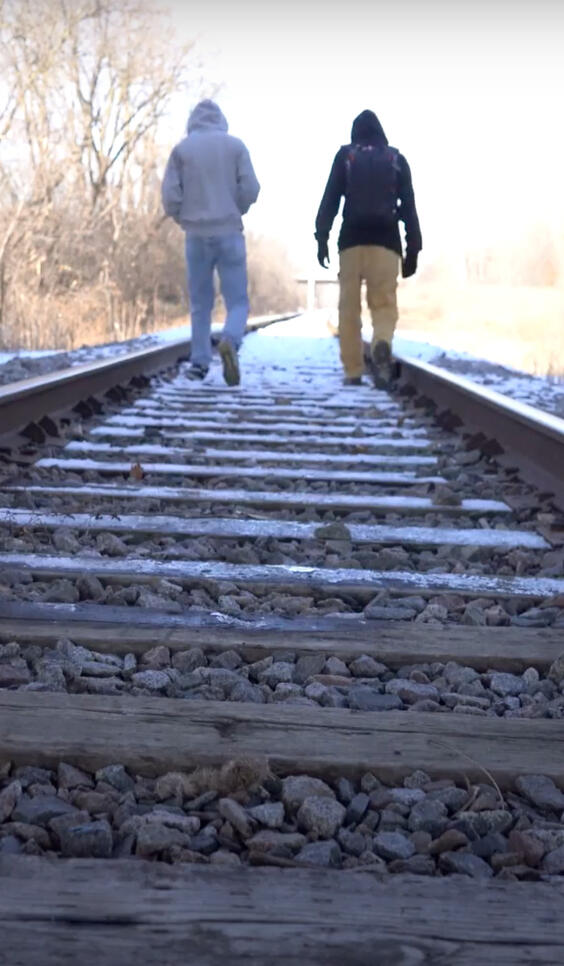 Screenshot of two people walking on train tracks ; Alvaro Serrano