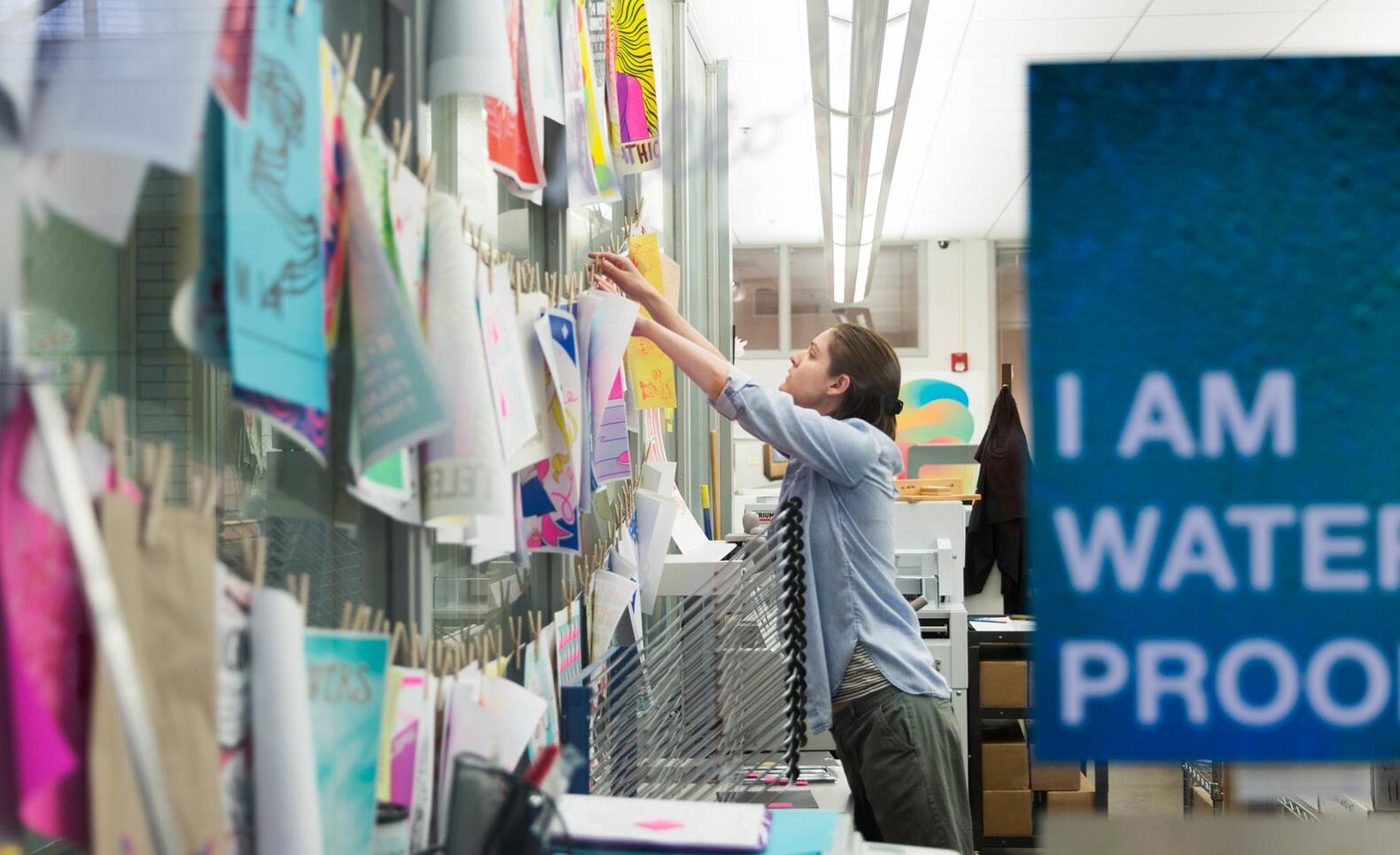 Person hanging up artwork in the Service Bureau