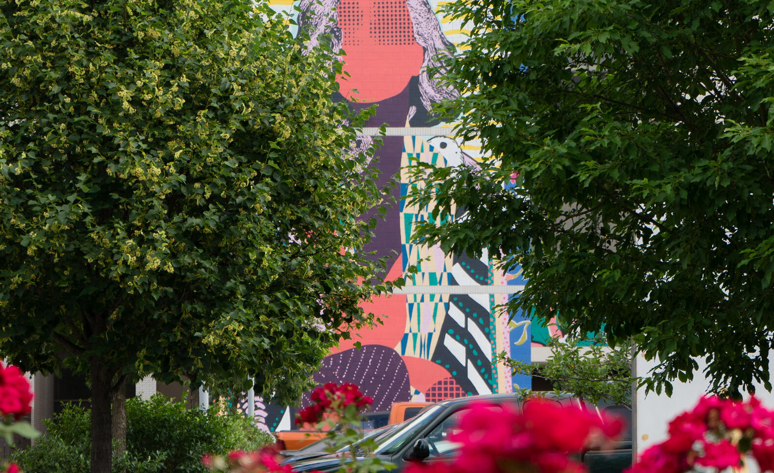 FAILE mural peeking through trees and flowers