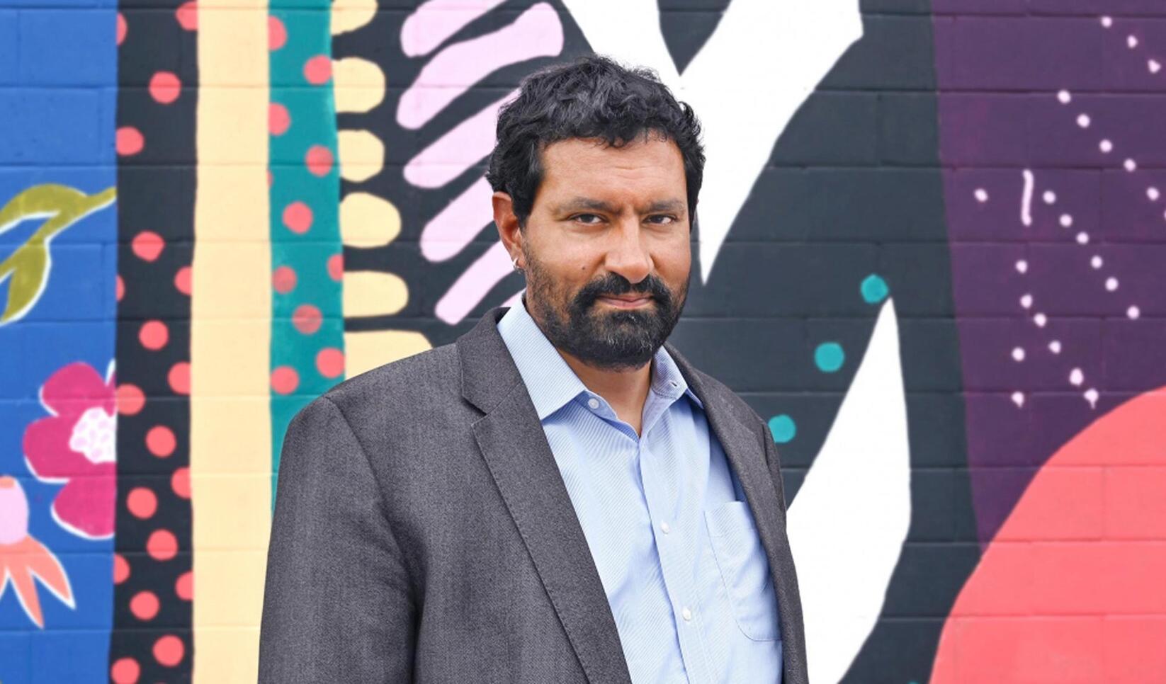 Portrait of Sanjit Sethi in front of the MCAD mural