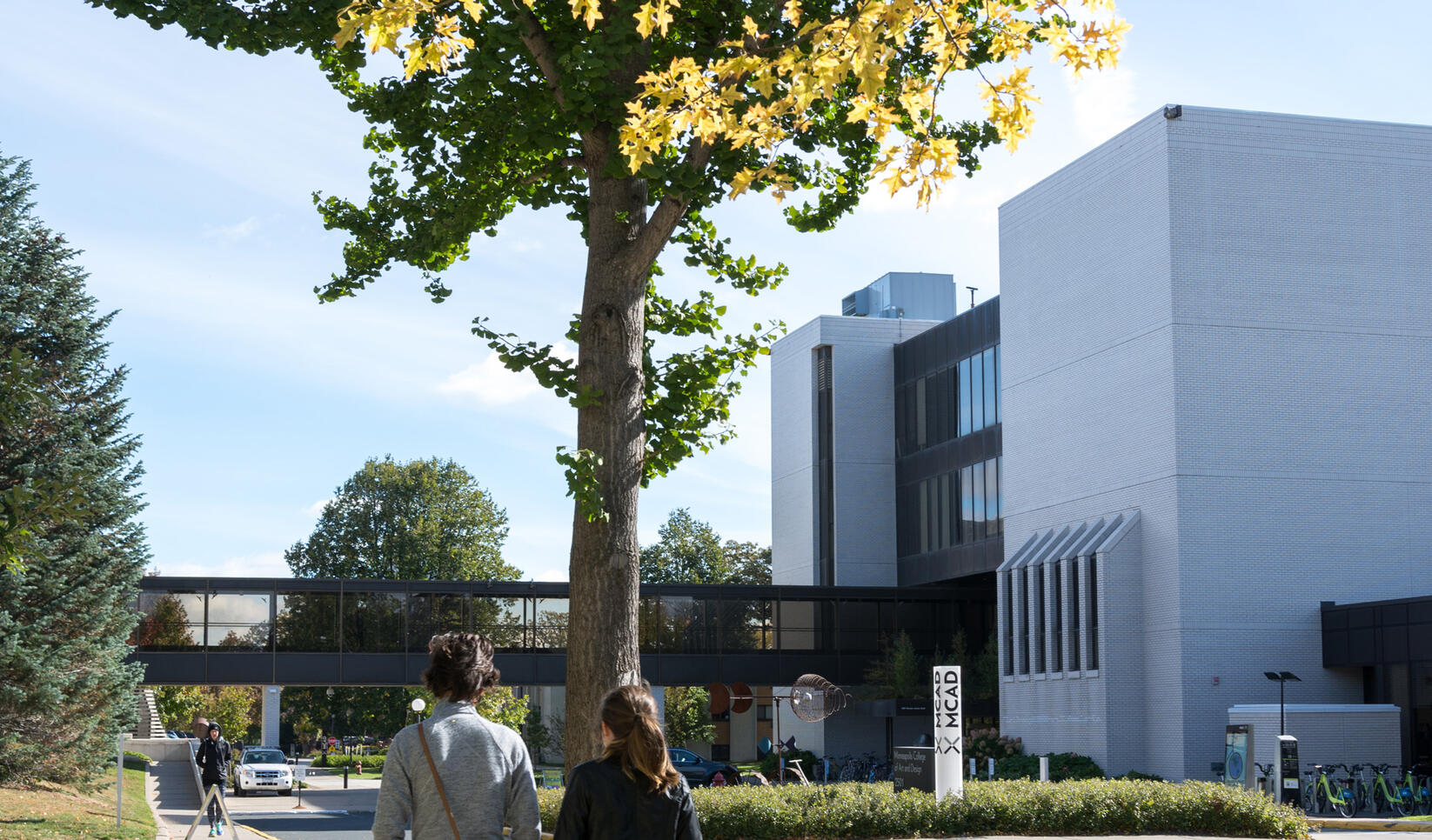 Two students walking towards MCAD in the fall