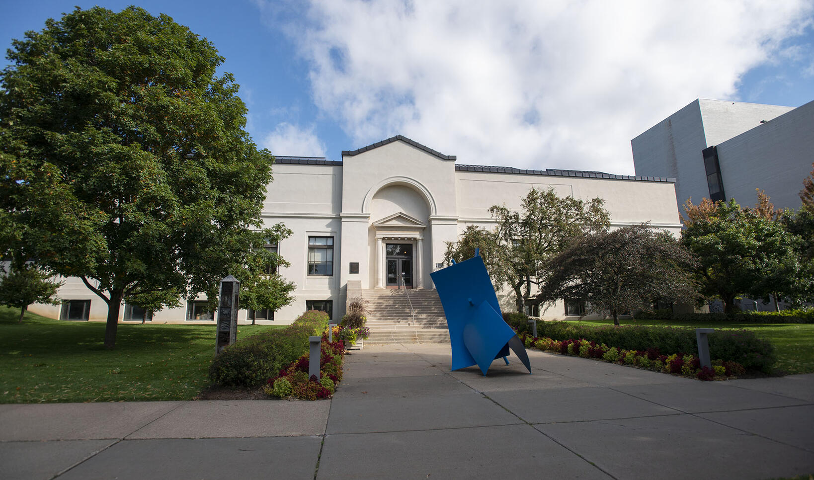 Front view of the Morrison Building with lush greenery and a blue abstract sculpture in the center.