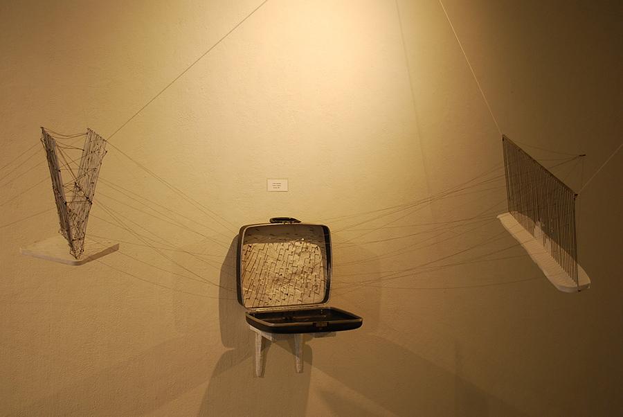 Mixed media sculpture composed of a suitcase, string, and other found materials.