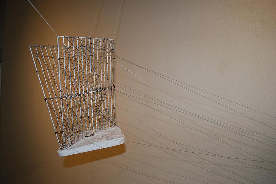 Mixed media sculpture composed of a suitcase, string, and other found materials.