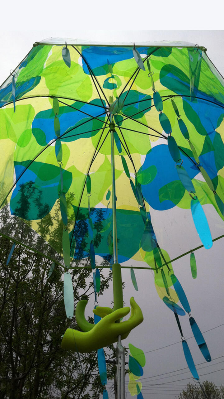 Public sculpture featuring sheets of blue and green, catching light. 