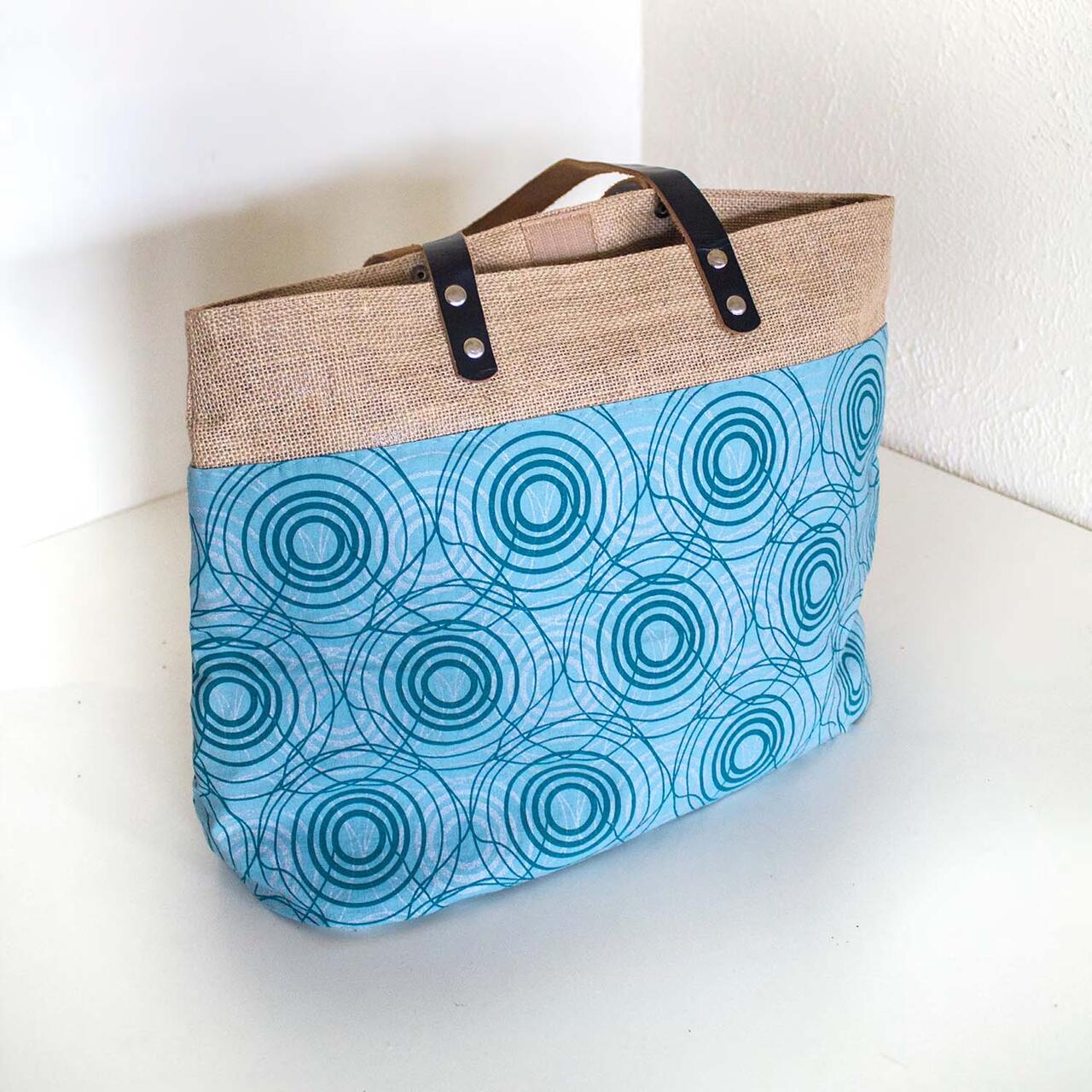 Tote bag composed of different materials, including printed fabric.