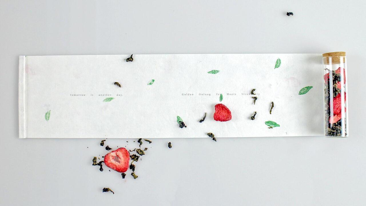 Photograph of a scroll, tea leaf, and strawberry