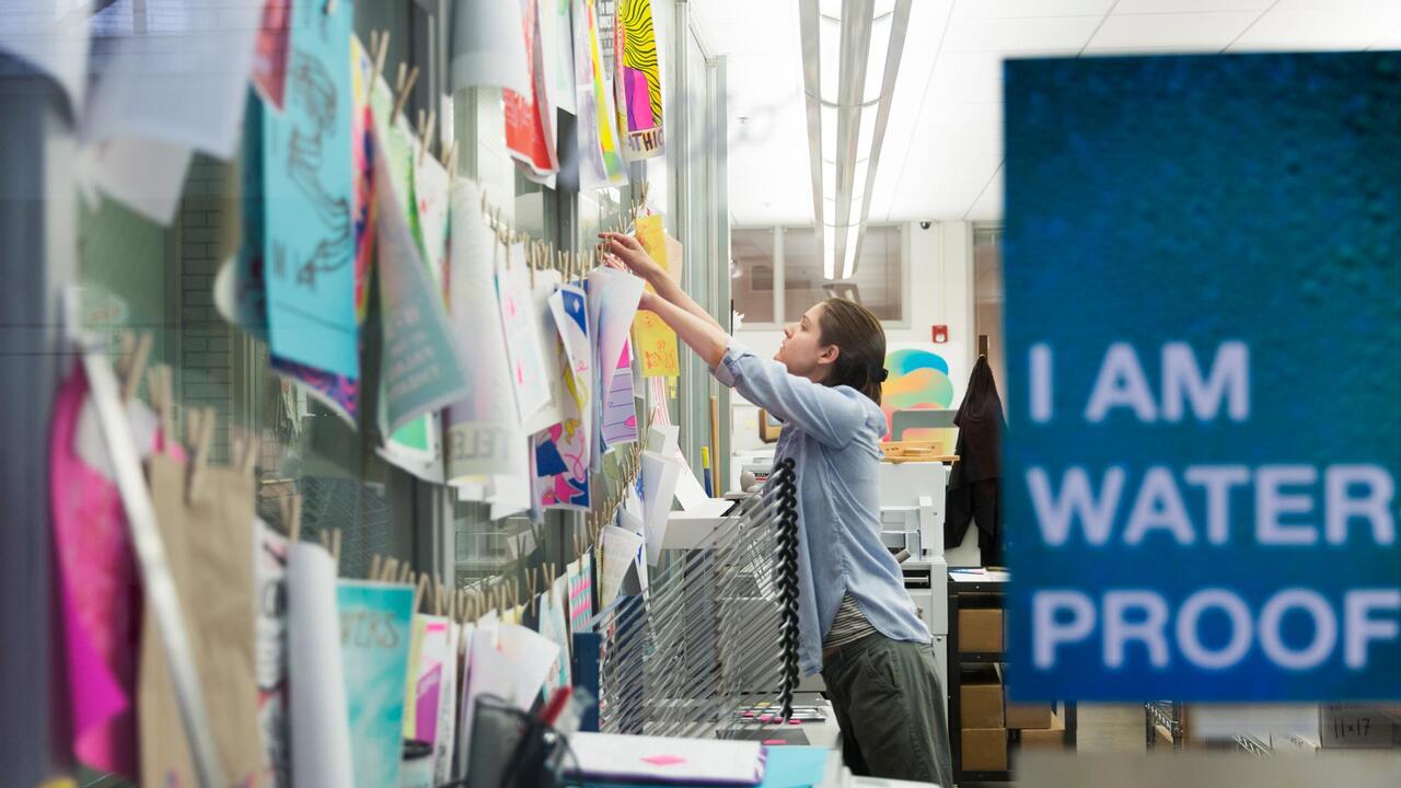 Person hanging up artwork in the Service Bureau