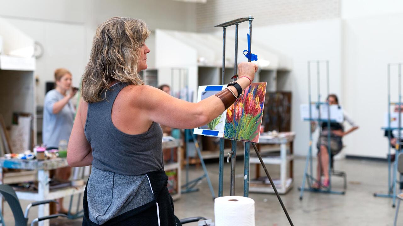 A continuing education student painting at an easel