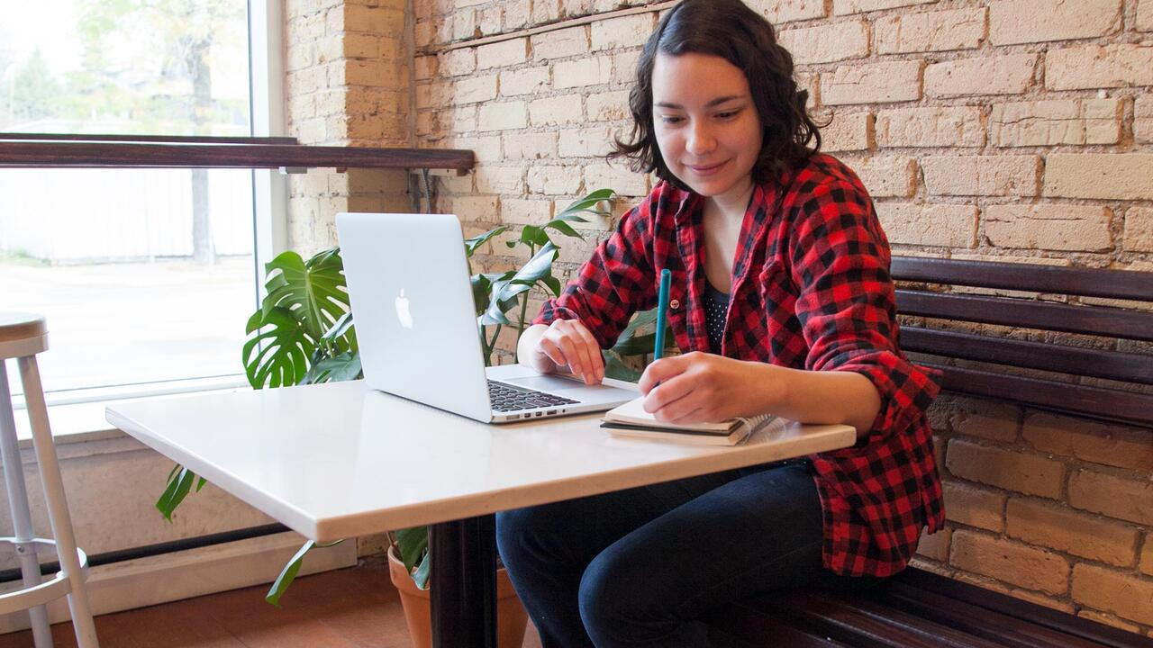 Student working in coffee shop at computer