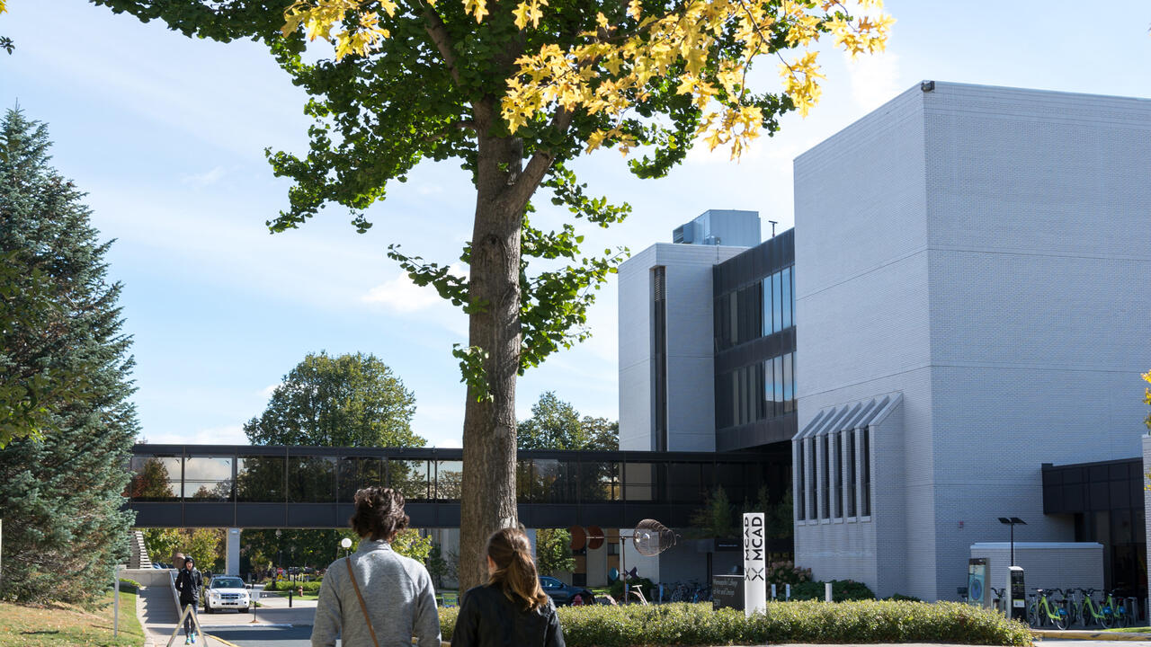 Two students walking towards MCAD in the fall