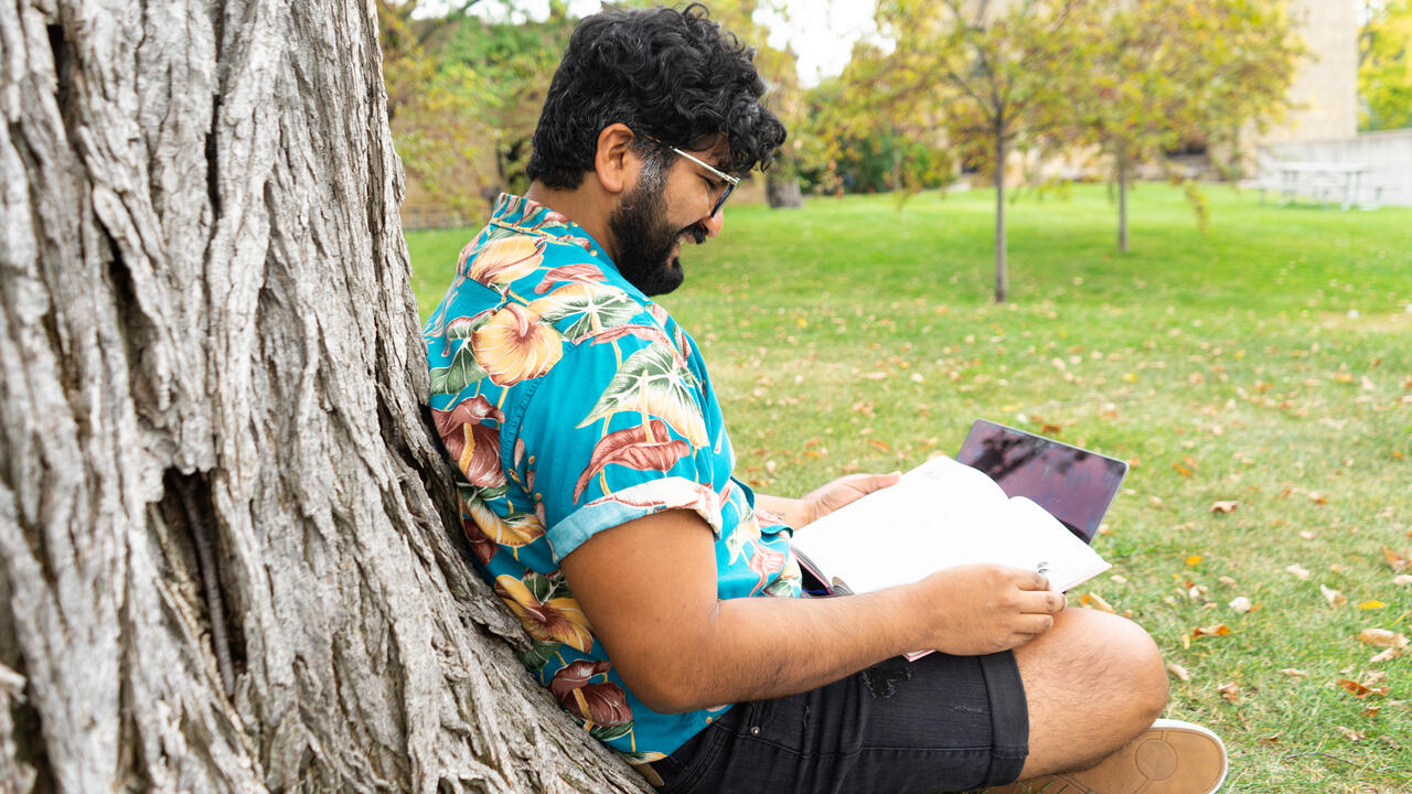 Student sitting under a tree working