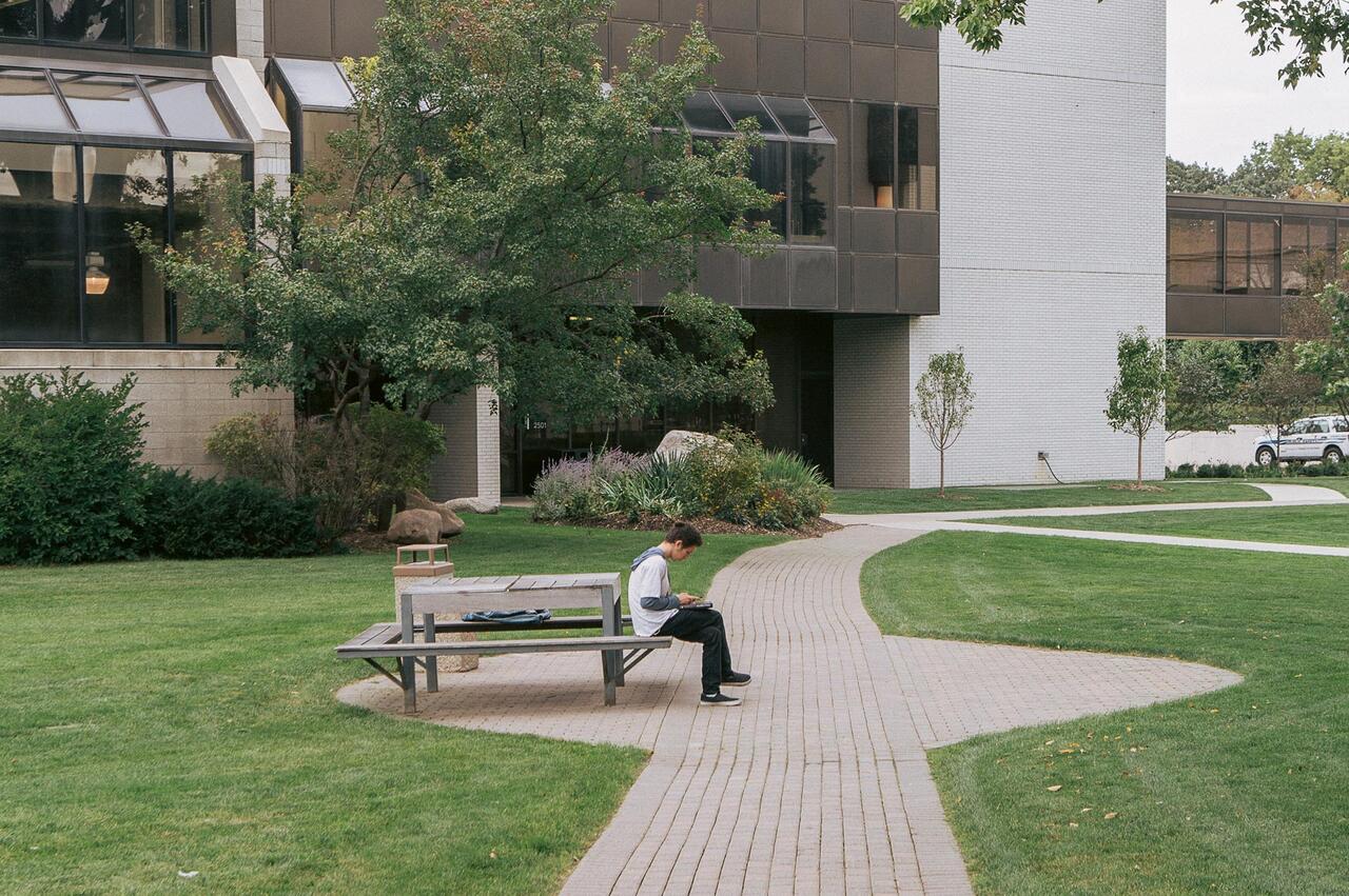 MCAD student on the MCAD lawn working on homework