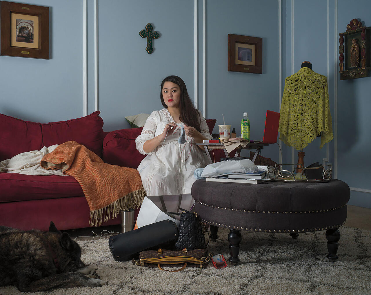 Color photo of a person in a living room knitting 
