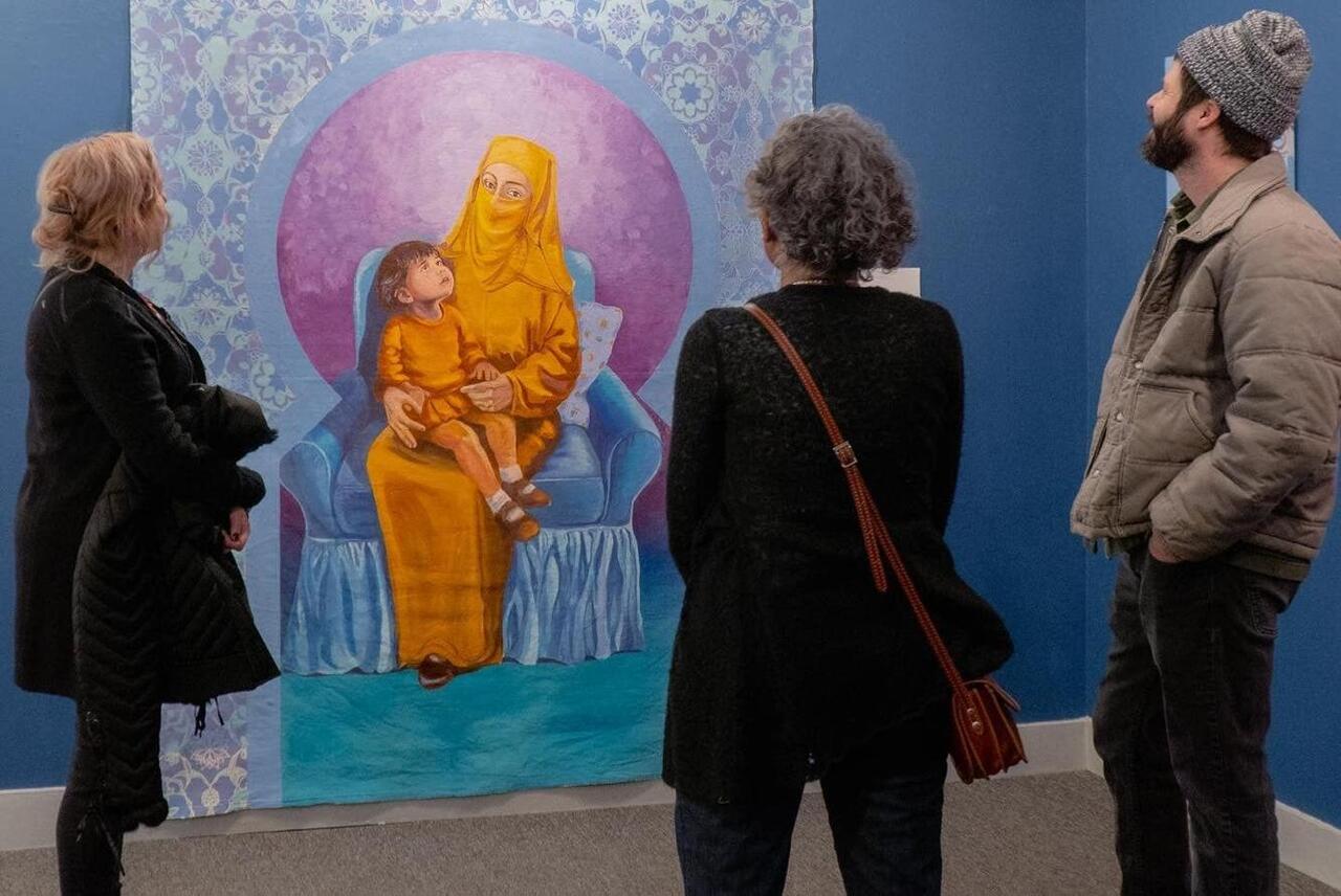 Viewers standing in front of a painting by Hend Al-Mansour