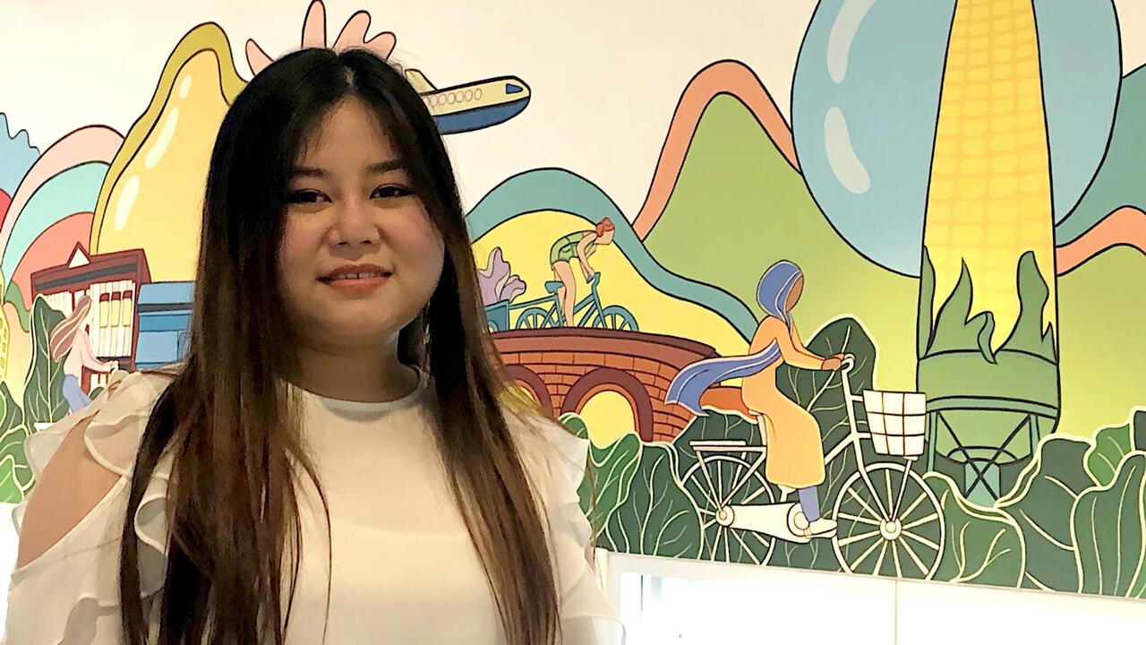 A woman stands infront of a large brightly colored mural