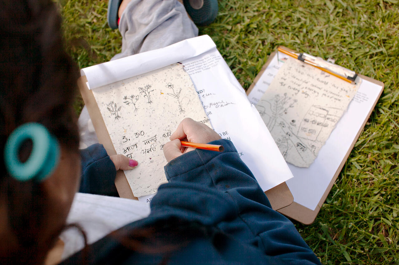 Photo of a person writing a letter while sitting on grass