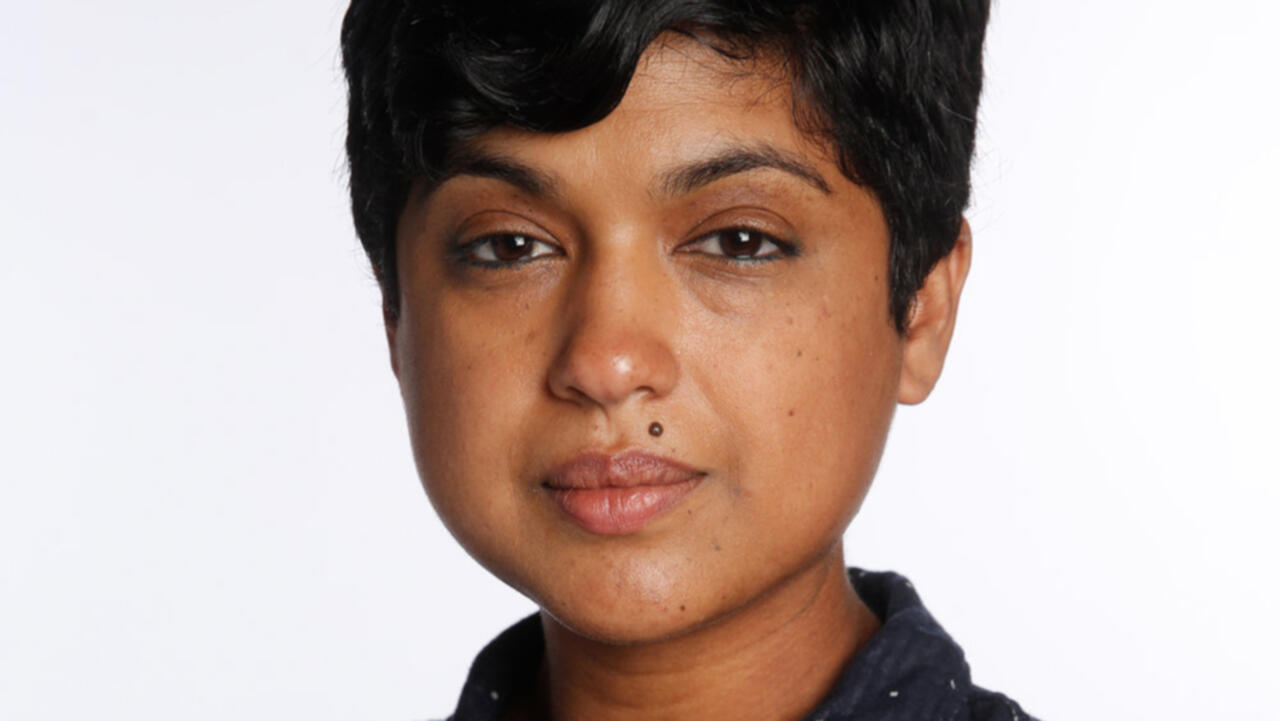 A close up image of a woman with brown skin, she is looking directly into the camera camera 