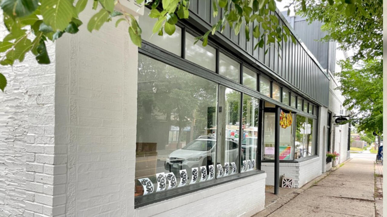 A photograph of Viewpoint Gallery, it is a white building with windows lining the front of the building with small posters decorating the windows