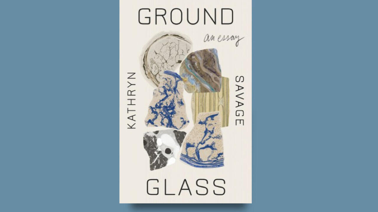 Cover of Ground Glass by Katheryn Savage, it is a small white book against a muted blue background. On the cover of the book there are several pieces of broken patterned glass.