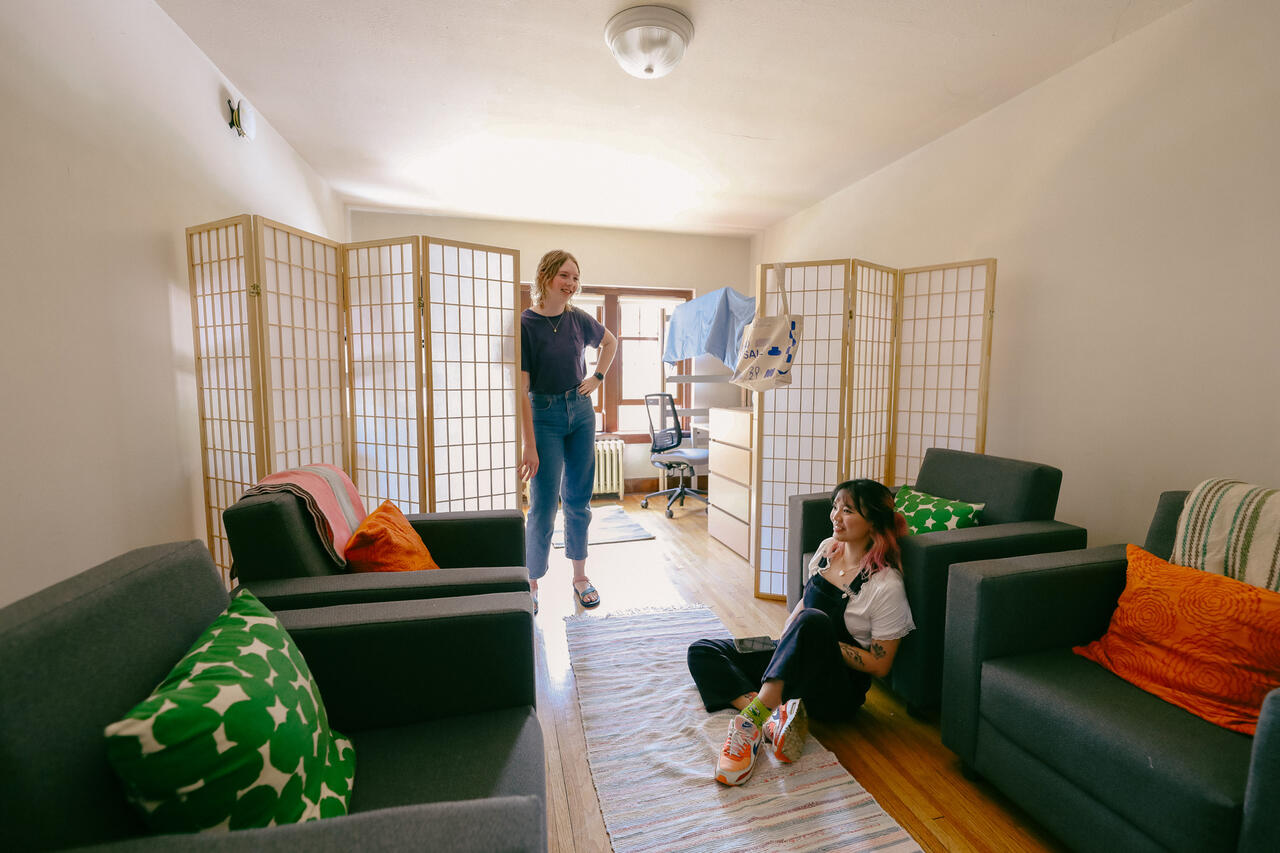 Two students talking in the living room of their apartment