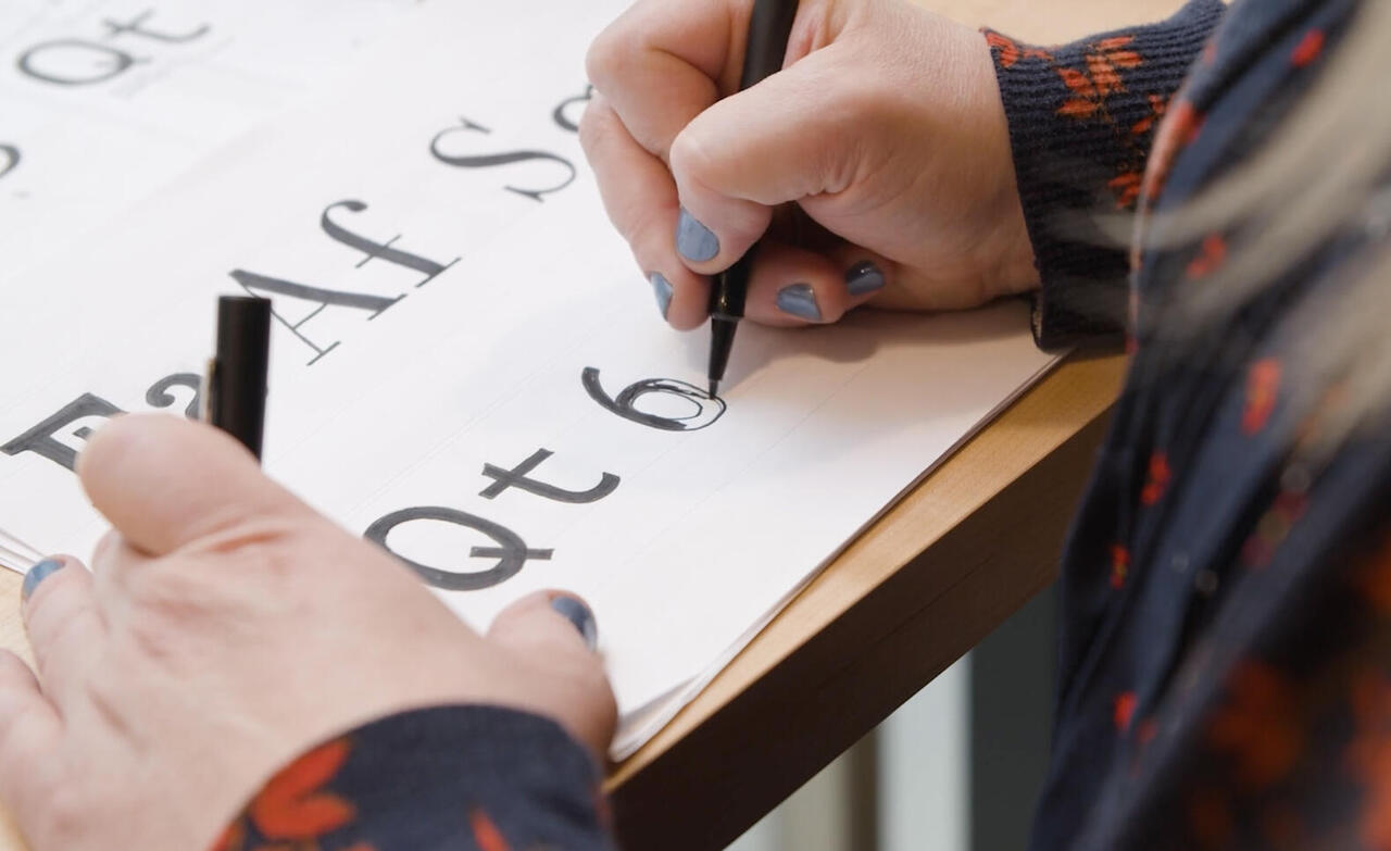 close up of hands drawing type face