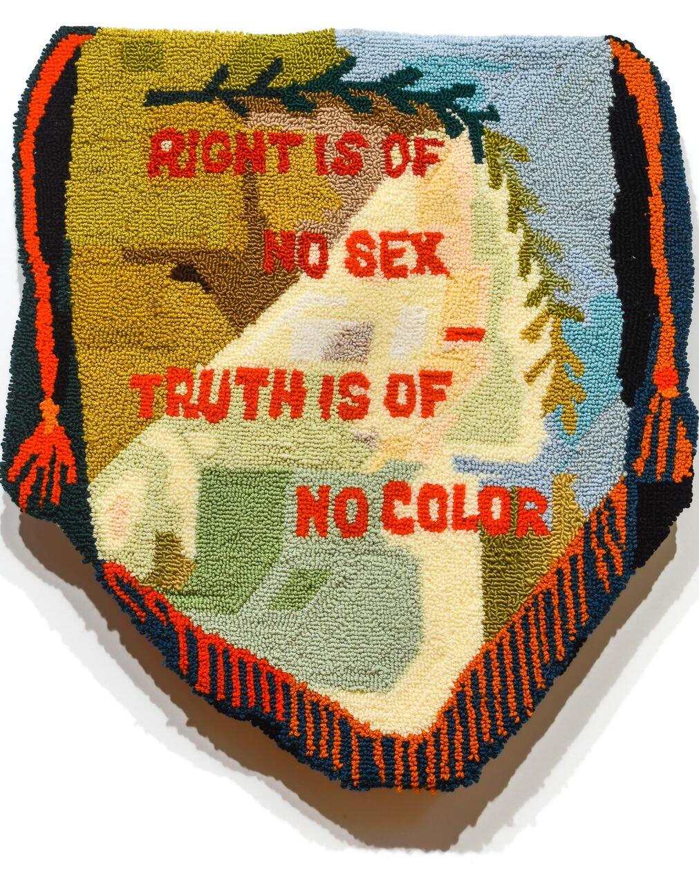 An embroidered rug with the text "RIGHT IS OF NO SEX - TRUTH IS OF NO COLOR" in red stitched writing on it.