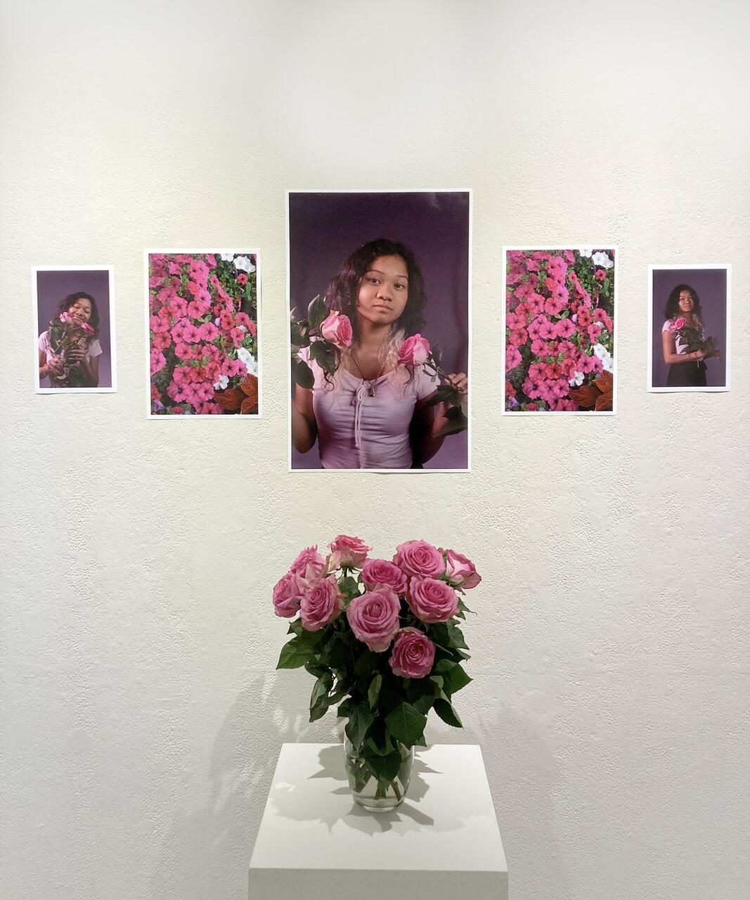 5 color photographs shown behind a bouquet of pink roses in a glass vase. The central image is the largest and shows the student looking directly into the camera holding two of the roses. Two images of different pink flowers can be seen to either side. Then, on the outsides are two more images of the student holding the roses in different poses.