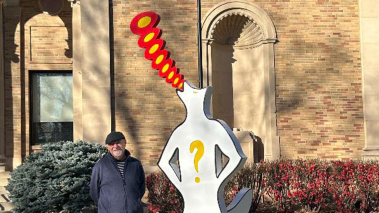 A large 3D outdoor sculpture of a man with a fox's head howling