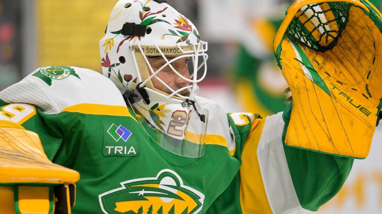 NHL Player Marc-Andre Fleury wearing his hockey uniform and a mask that has different Native American symbols and imagery on it