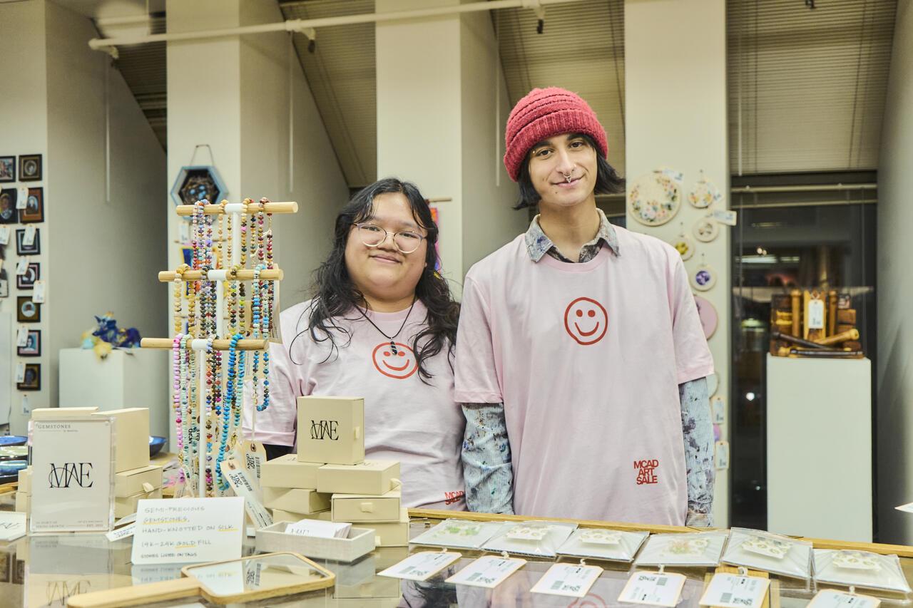 Two students working at the MCAD Art Sale